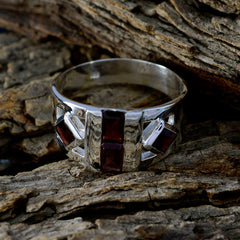 Evelyn abstract red gemstone ring with silver band displayed on rustic wood background