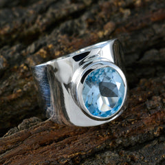 Bianca blue gemstone solitaire ring with polished silver band on rustic wood background