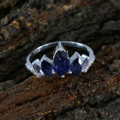 Rina elegant blue gemstone crown ring with silver band and marquise-cut stones on rustic wood