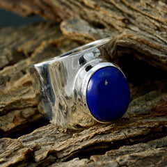 Sofia blue solitaire gemstone ring with polished silver band resting on textured wood