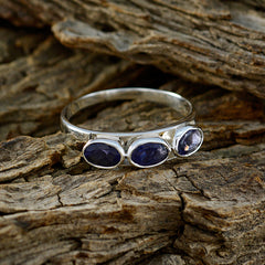 Lily blue trilogy gemstone ring with three blue stones set in silver band on textured wood