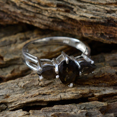 Jiwoo brown gemstone trilogy ring with three oval brown stones set in silver band on rustic wood
