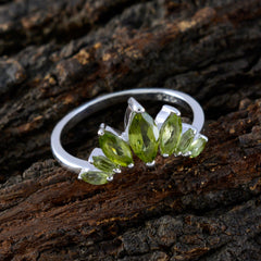Kristine green gemstone crown ring with marquise-cut stones set in silver band on rustic wood