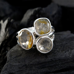 Florencia modern golden trilogy ring with three clear gemstones set in silver band on dark textured background