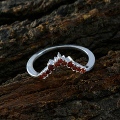 Silver Putri red crown ring for women with red gemstones on textured wooden background