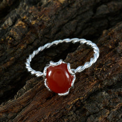 Ying red gemstone solitaire ring with twisted silver band on rustic wooden background