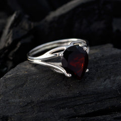Soo-jin red solitaire gemstone ring with pear-shaped red gemstone and silver band on dark surface