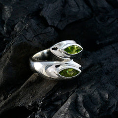 Lara abstract green toi et moi ring featuring two green gemstones set in silver band on dark textured background