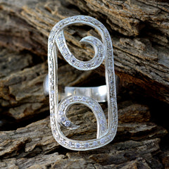 Ella abstract white statement ring with intricate swirl design and embedded stones on rustic wood background