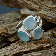 Silver aqua gemstone trilogy ring with three light blue stones set on textured wood background