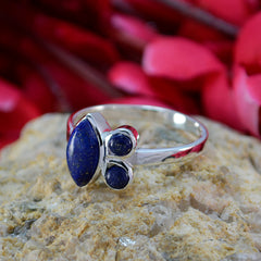 Carla artisan blue gemstone ring with three polished blue stones set in silver band on textured rock