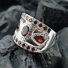 Bianca artisan red gemstone ring with intricate silver design and multiple red stones on textured black background