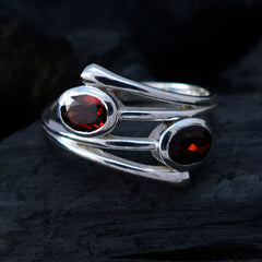 Silver artisan toi et moi ring with two oval red gemstones on a dark background