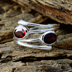 Silver artisan toi et moi ring with two red oval gemstones on rustic wood background