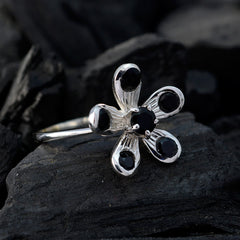 Priya black gemstone flower ring with silver band displayed on dark textured surface