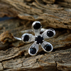 Priya black gemstone flower ring with five black stones set on a silver floral band on textured wood