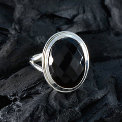 black solitaire ring for women Dewi oval faceted black stone in silver bezel setting on dark textured background