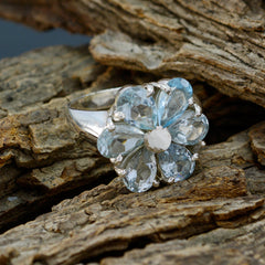 Lucia blue floral gemstone ring with silver band on textured wood background