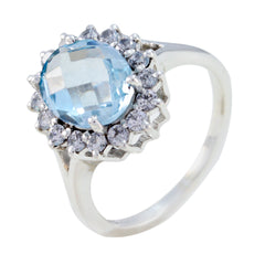 Violet blue gemstone fashion ring with faceted oval blue stone and halo of clear stones on silver band