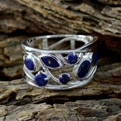 Nora blue gemstone filigree ring with silver band and intricate leaf design on rustic wood