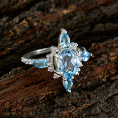 Marie blue gemstone statement ring with multiple blue stones set in silver on textured wood background