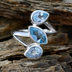 Bianca blue gemstone trilogy ring with three mixed cut blue stones in sterling silver band on wood background