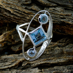 Leah silver blue gemstone trilogy ring with square and round stones on rustic wood