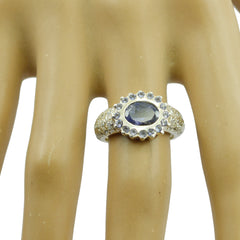 Lucia blue halo engagement ring with oval blue gemstone and surrounding clear stones on a display hand
