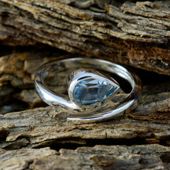 Violet brand blue solitaire ring with pear-shaped blue gemstone set in a polished silver band on wood