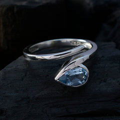 Violet silver blue solitaire ring with a pear-shaped blue gemstone on a dark textured surface