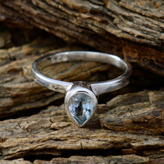 Natcha blue solitaire ring with pear-shaped blue gemstone set in silver band on rustic wood