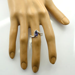 Meera blue solitaire ring with a teardrop-shaped blue gemstone on a silver band shown on a hand model