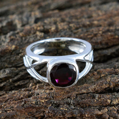 Cecilia boho red solitaire ring with a deep red cushion gemstone and silver band on rustic wood