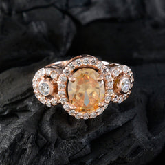 Xiu brown gemstone halo ring with oval center stone and sparkling diamond accents on dark background