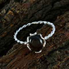 Liyana brown solitaire gemstone ring with twisted silver band on rustic wood background