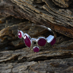 Kennedy contemporary red gemstone ring with multiple red stones set in silver band on textured wood