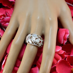 Aurora contemporary white gemstone ring with floral design on hand over red rose petals