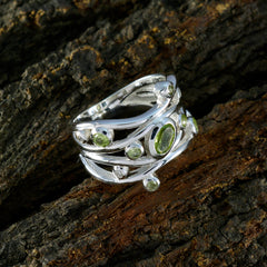 Nisa fairytale brown gemstone ring product photo showing silver multi band ring with green peridot stones on dark bark background