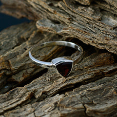 Emilia geometric red solitaire ring with triangular red gemstone on silver band resting on textured wood