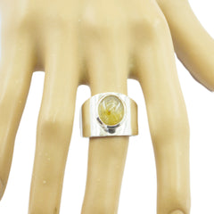 Skylar golden solitaire ring with a wide band and an oval gemstone on a display hand