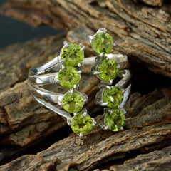 Eleanor green gemstone octagon ring featuring six bright round peridot stones in a silver multi band setting on wood