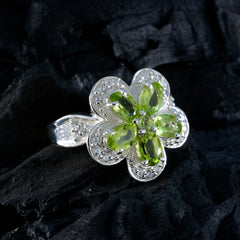 Victoria green gemstone statement ring with flower design and silver band on black textured surface