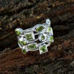 Julieta green gemstone statement ring with multiple green stones set in silver band on rustic wood background