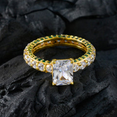 Teresa green halo engagement ring with gold band and rectangular center stone on black textured background