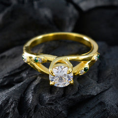 Meera gold ring featuring a clear center stone with green halo ring for women on black textured surface