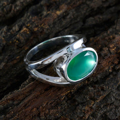 Emma heritage green gemstone ring with polished silver band resting on textured wood
