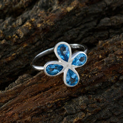 Yan silver blue floral gemstone ring featuring four pear cut blue gemstones in a floral motif on bark