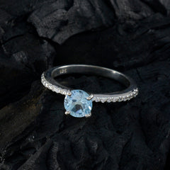 Silver blue halo ring with a round light blue gemstone and small clear stones on the band