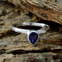 Mei blue solitaire gemstone ring with pear-shaped blue stone set in silver band on rustic wood
