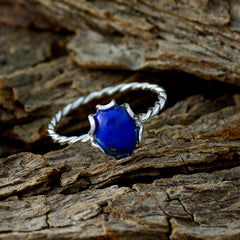 Riya blue solitaire twist ring with deep blue stone and twisted silver band on rustic wood